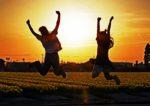 チューリップ畑の夕日をバックに2人で手を上げて飛び上がっている写真