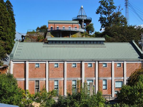 下山芸術の森・発電所美術館の外観を撮影した写真。建物は赤のレンガ造りに緑色の屋根で作られている。