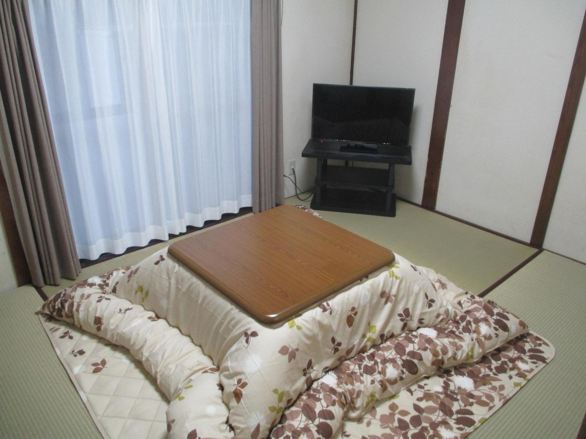 和室の内観を撮影した写真。奥にはテレビ、部屋の中央にはコタツが置かれている。
