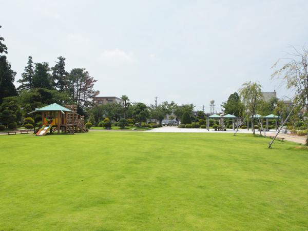 花月公園の写真。手間には広い芝生が広がっており、左奥には小さな滑り台がある。