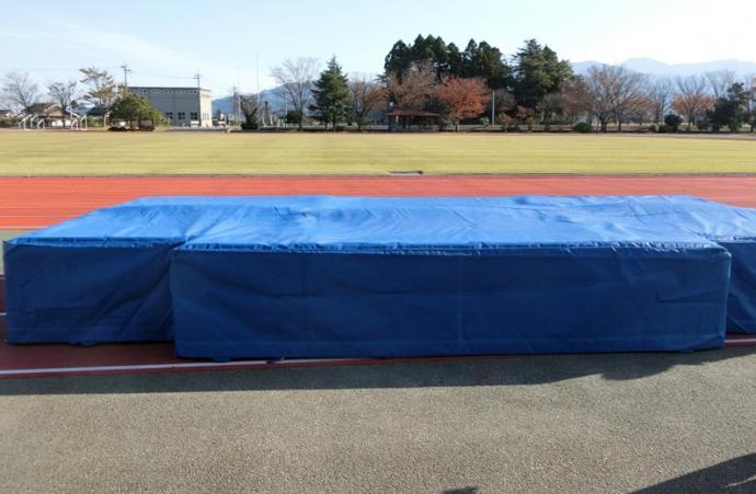入善町中央公園陸上競技場の走行レーンの脇に設置されている青色の厚みのある走高跳用マットの写真