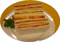 スライスしたトマトを、まるでイチゴサンドのように肉厚に挟み、お皿の上に並べたサンドイッチの写真