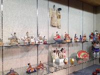 日本各地の郷土玩具などのコレクションが壁や三段の棚にずらりと展示されている様子の写真