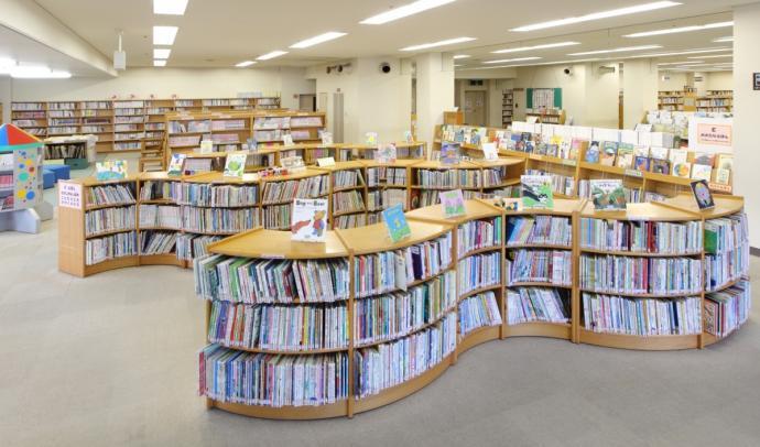 図書館内を撮影した写真。丸みを帯びた背の低い珍しい本棚に、たくさんの本が並んでいる。