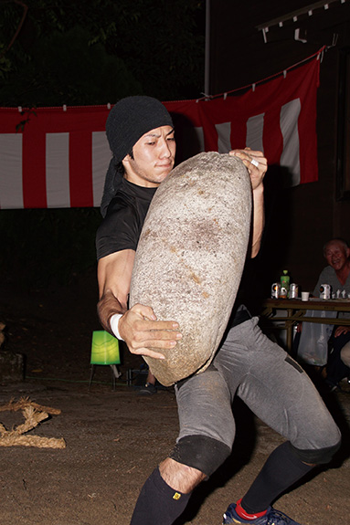 新屋住吉社の大磐祭りで100キログラム超の巨石を持ち上げている男性の写真