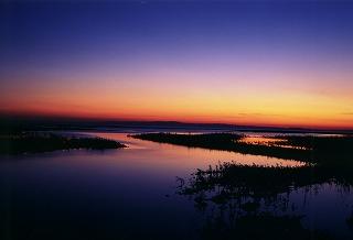 夕暮れの茜色から濃紺へのグラデーションが鮮やかな空。手前にはその色を鮮やかに映し出した黒部川河口の水面の写真