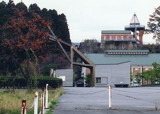赤レンガ、緑の屋根の発電所美術館の建物と左に並んだ紅葉した木々の写真