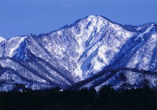 青空のもと雪化粧した負釣山の写真