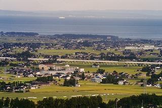 高台から青い日本海と色づく田んぼと街並みを見下ろした入善町の写真