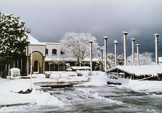 冬曇りの中、雪に覆われた町民会館と駐車場の写真