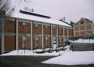 雪景色、冬曇りの中に建つレンガ造りの建物の写真